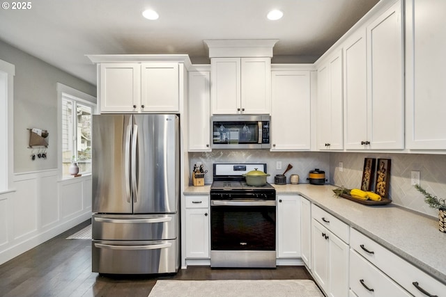 kitchen featuring tasteful backsplash, dark wood finished floors, wainscoting, appliances with stainless steel finishes, and white cabinets