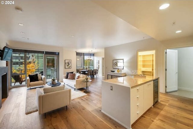 living area featuring wine cooler, a fireplace, light wood finished floors, recessed lighting, and baseboards