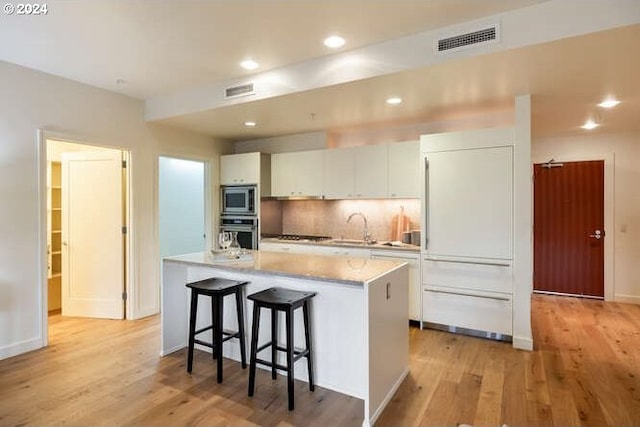 kitchen with white cabinets, a kitchen island, visible vents, and stainless steel appliances