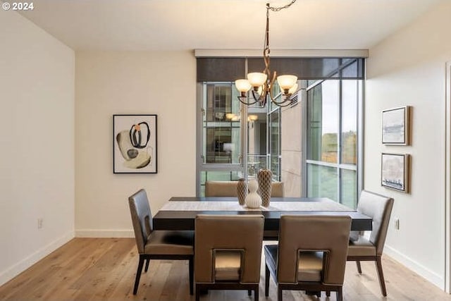 dining room featuring expansive windows, a notable chandelier, light wood-style flooring, and baseboards