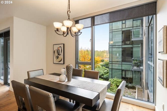 dining space with a wall of windows, a notable chandelier, and wood finished floors