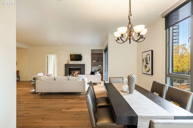 dining room featuring a wall of windows, a fireplace, wood finished floors, and an inviting chandelier