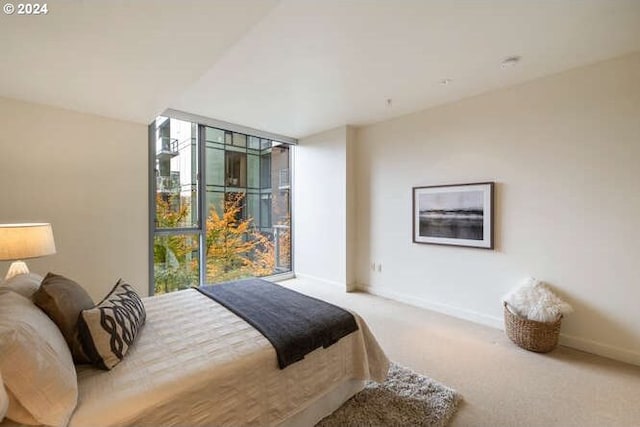 carpeted bedroom featuring a wall of windows and baseboards