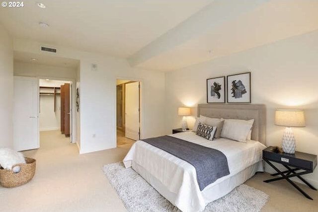 bedroom featuring visible vents, a walk in closet, and light colored carpet