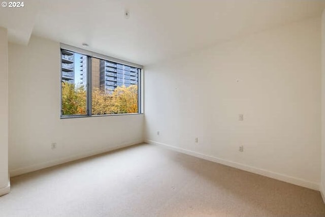 spare room with light carpet and baseboards