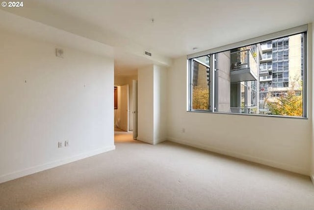 unfurnished room featuring a healthy amount of sunlight, baseboards, visible vents, and carpet floors