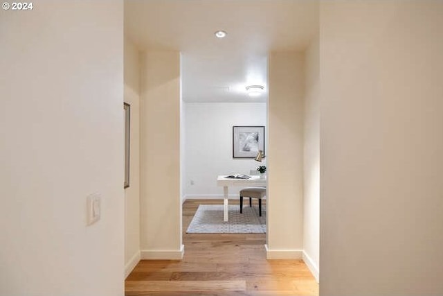 hall with light wood-style flooring and baseboards