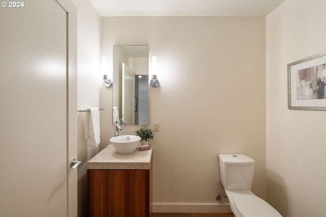 bathroom with toilet, vanity, and baseboards