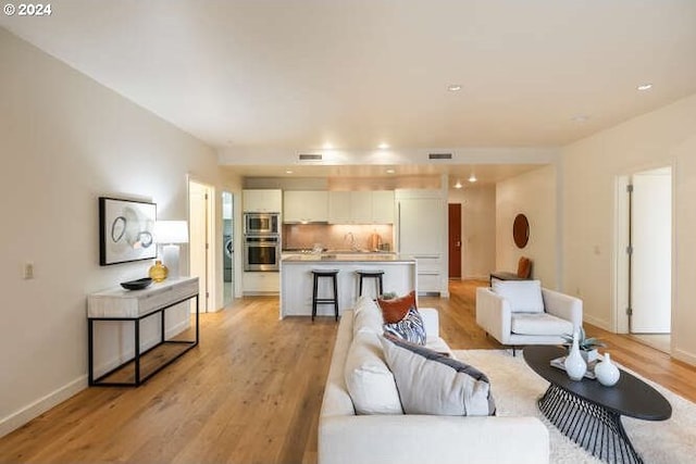 living area with baseboards, visible vents, and light wood finished floors