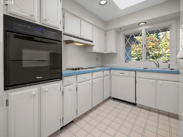 kitchen with a skylight, white appliances, sink, and white cabinets