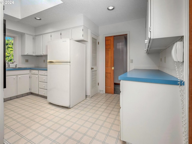 kitchen featuring white cabinets, a textured ceiling, and white fridge