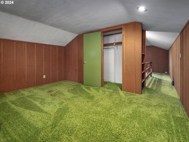 additional living space with wood walls, carpet floors, and vaulted ceiling