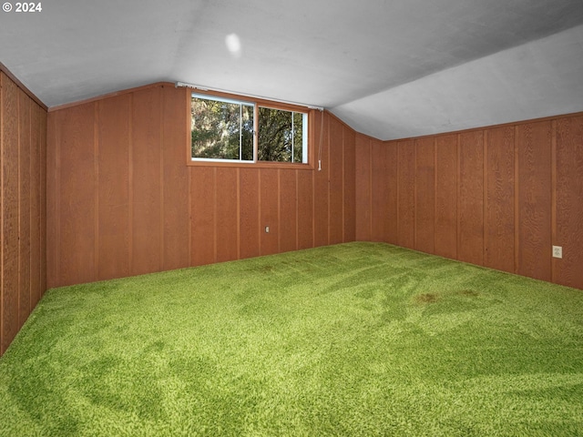 additional living space with carpet flooring, wooden walls, and vaulted ceiling