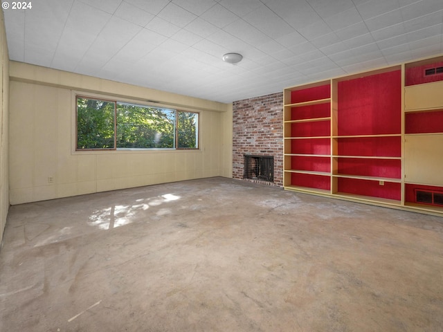 unfurnished living room with a brick fireplace and concrete flooring