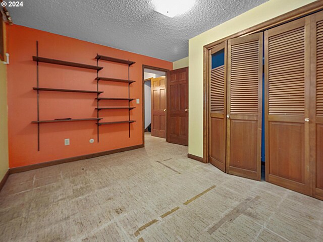 unfurnished bedroom featuring light carpet, a textured ceiling, and a closet