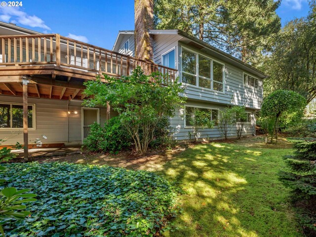 back of house featuring a wooden deck and a lawn