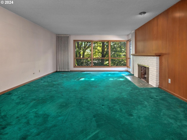 unfurnished living room featuring carpet floors, a textured ceiling, a brick fireplace, and wood walls