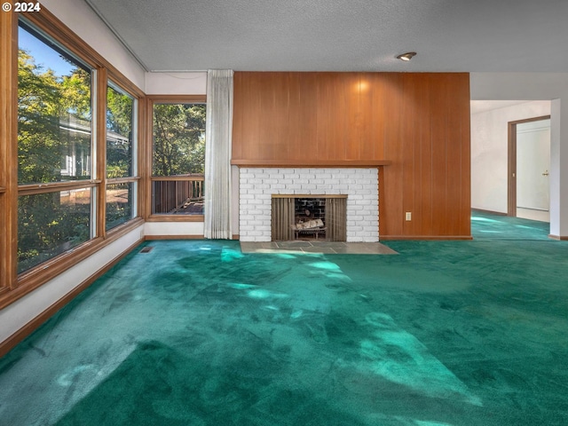 unfurnished living room featuring carpet floors, a brick fireplace, wooden walls, and a textured ceiling