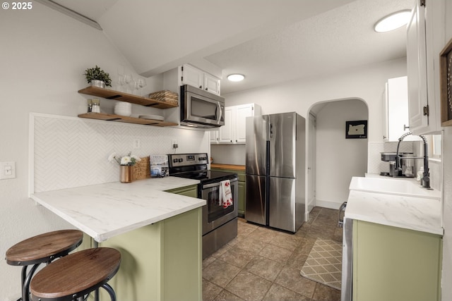 8413 SW 4th Ave, Portland, OR 97219 - kitchen with appliances with stainless steel finishes, a breakfast bar, decorative backsplash, a peninsula, and green cabinets