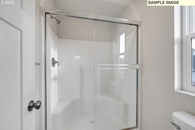 bathroom with a shower with door and toilet