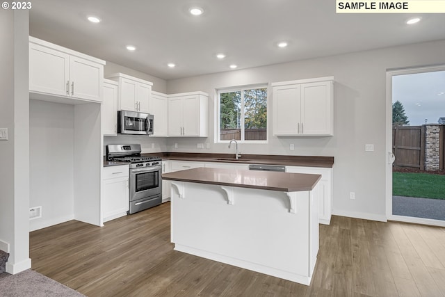 kitchen featuring a kitchen island, dark hardwood / wood-style floors, sink, white cabinets, and appliances with stainless steel finishes