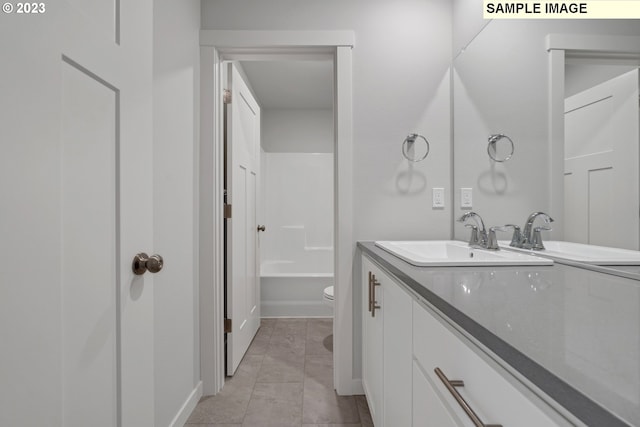 bathroom with a tub to relax in, vanity, toilet, and tile patterned flooring