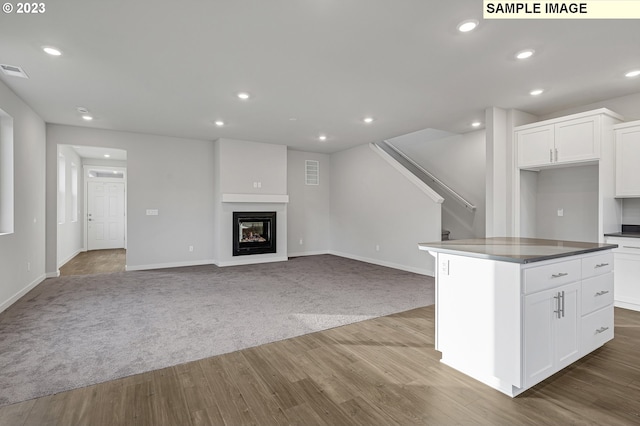 kitchen featuring white cabinetry, light carpet, and a center island