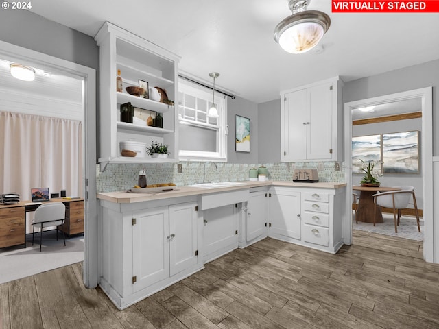 kitchen featuring white cabinets, light wood-type flooring, decorative backsplash, and hanging light fixtures