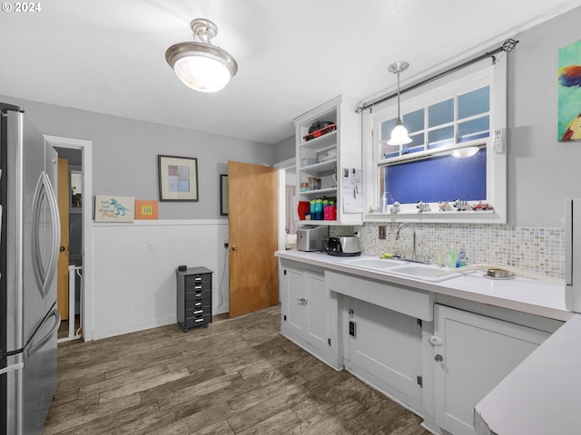 kitchen with white cabinets, sink, decorative light fixtures, and stainless steel refrigerator