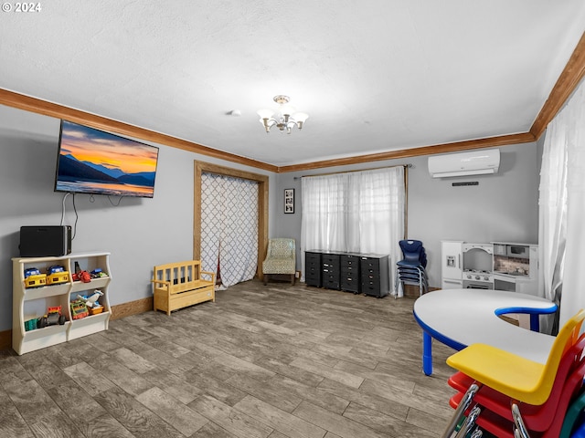 playroom with a wall mounted AC, a notable chandelier, crown molding, and wood-type flooring