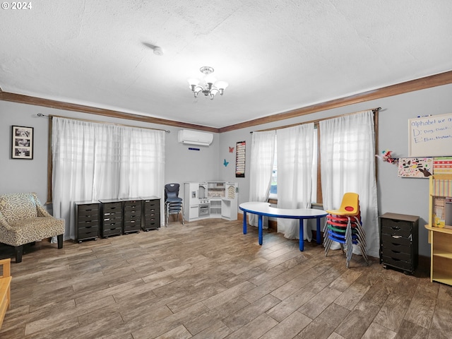 recreation room featuring a textured ceiling, hardwood / wood-style flooring, a wall mounted AC, and crown molding