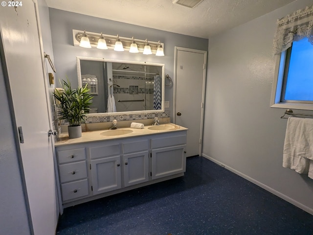 bathroom with vanity, a textured ceiling, and walk in shower