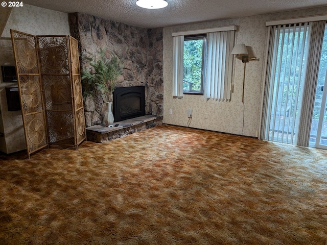 unfurnished living room with carpet, a textured ceiling, and a stone fireplace