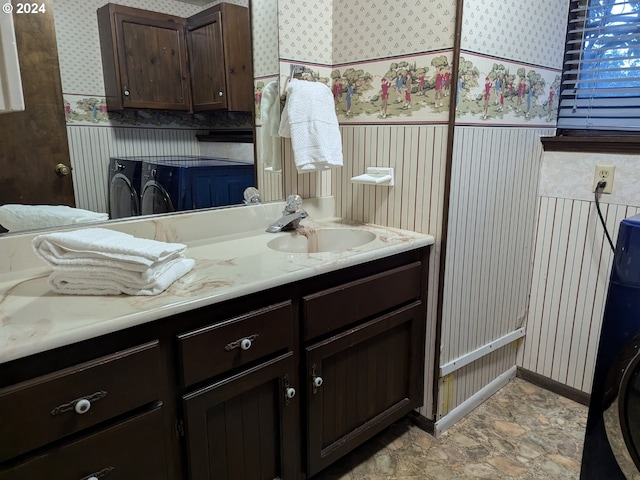 bathroom with vanity, washing machine and clothes dryer, and wallpapered walls
