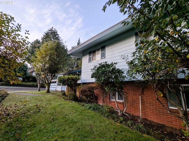 view of side of home featuring brick siding and a lawn