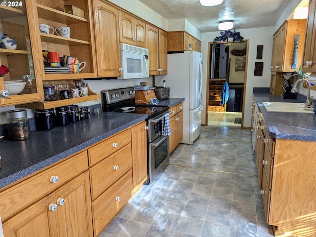 kitchen featuring a textured ceiling, white appliances, and sink