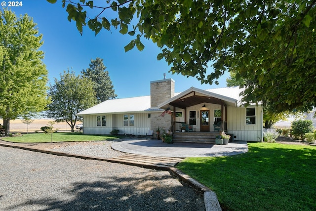 48612 Duff Rd, Adams, OR 97810 - view of front of house featuring a chimney, a front yard, board and batten siding, and covered porch