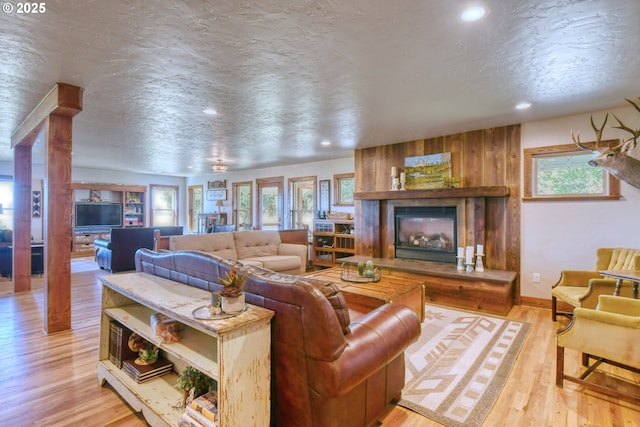 living room with a fireplace, a textured ceiling, and light wood-type flooring