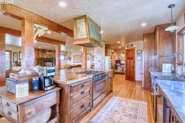 kitchen with sink, pendant lighting, light hardwood / wood-style floors, a textured ceiling, and high end range