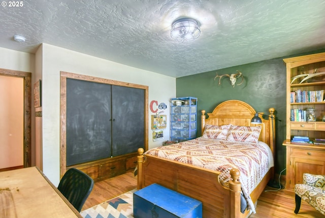 bedroom with a closet, light hardwood / wood-style flooring, and a textured ceiling