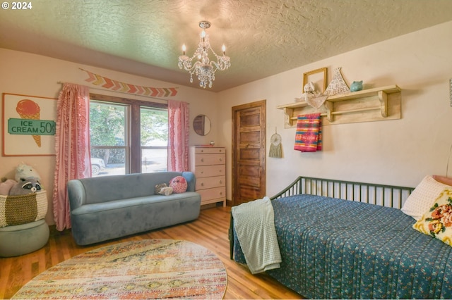 bedroom with hardwood / wood-style flooring, a textured ceiling, and an inviting chandelier