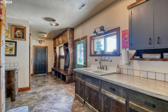 kitchen featuring dark brown cabinetry, sink, and a textured ceiling