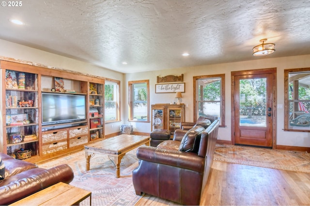 living room featuring plenty of natural light, light hardwood / wood-style floors, and a textured ceiling