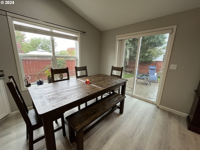 dining space with light wood-type flooring, vaulted ceiling, and a healthy amount of sunlight