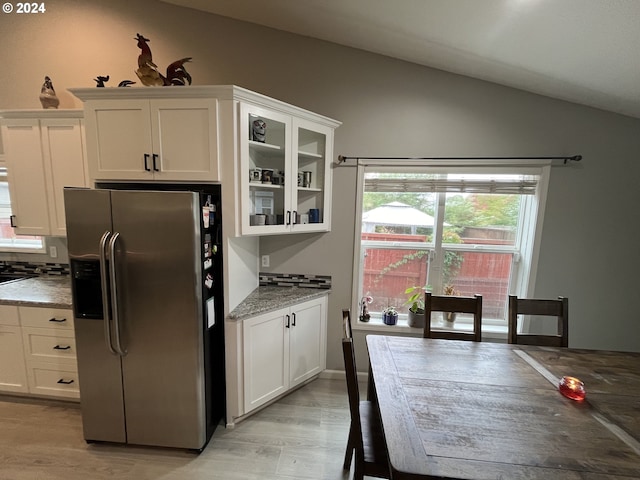 kitchen with stainless steel fridge with ice dispenser, white cabinets, lofted ceiling, light hardwood / wood-style flooring, and light stone countertops