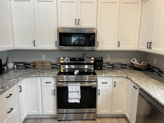 kitchen featuring light stone countertops, stainless steel appliances, white cabinetry, and light hardwood / wood-style flooring