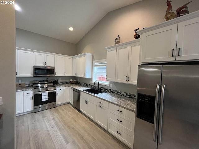 kitchen featuring light stone counters, lofted ceiling, stainless steel appliances, and white cabinets