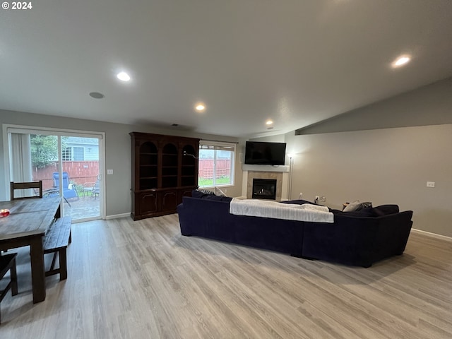 living room with a tiled fireplace, light hardwood / wood-style flooring, and a wealth of natural light