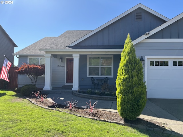 view of front facade with a front yard, a garage, and covered porch