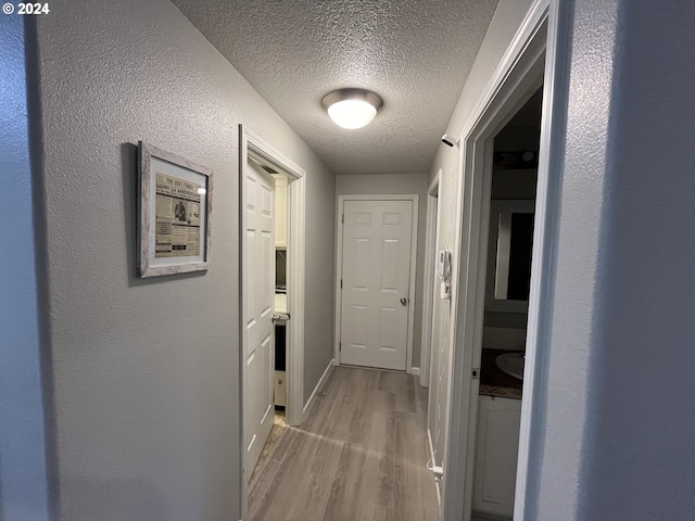 hallway featuring light wood-type flooring and a textured ceiling